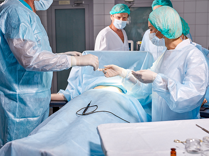 a team of surgeons and assistants handing over tools to one another in an operating theatre