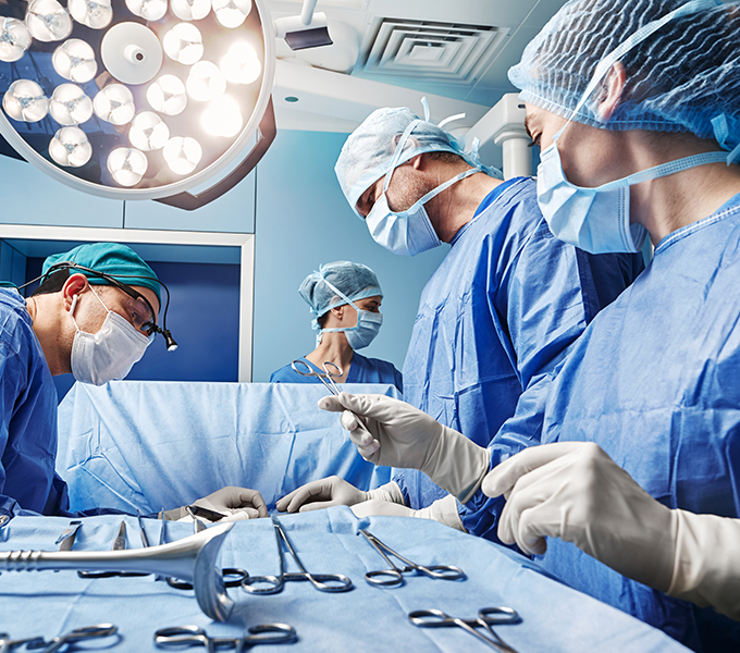 a consultant and three assistants using surgical tools in a surgery in an operating theatre